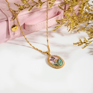 Détail d'un collier vintage avec pendentif ovale papillon et fleur sur chaîne dorée