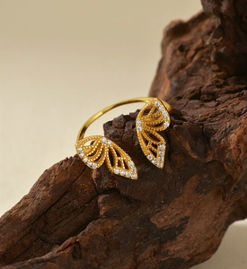 Macro shot of gold butterfly ring with white zircon wings on rustic wood base
