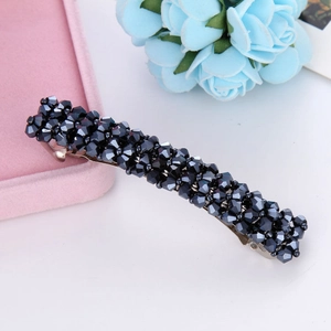 Close-up of luxury hair clip with navy blue crystals on pink velvet jewelry box display