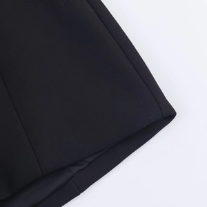 Close-up of the black woven fabric texture and hem stitching on short romper