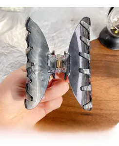 Detailed view of butterfly hair claw with grey marble texture and gold metal spring