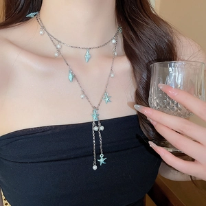 Détail d'un collier double épaisseur avec perles et pendentifs étoile de mer bleue