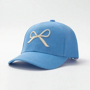 Detail view of 3D beige bow embroidery on a light blue cotton twill baseball cap