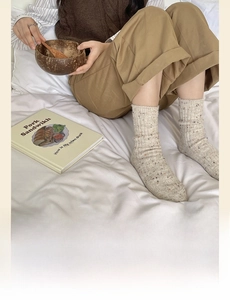 Close-up of thick knitted wool socks in off-white with speckled texture for winter