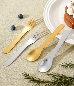 Close-up of elegant gold and silver stainless steel dessert spoons and forks on a table