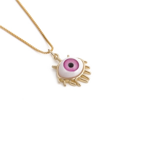 Macro shot of gold-plated box chain and evil eye pendant with pink iris and metal lashes