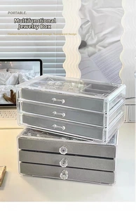 Close-up of clear acrylic jewelry box with velvet drawers and crystal handles for rings