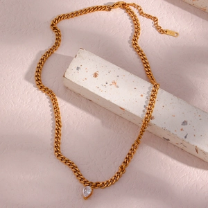 Detail showing gold Cuban chain necklace with teardrop zircon and 18K engraved tag
