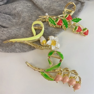 Detail of tulip, strawberry and lily floral hair claws with pearl and enamel accents