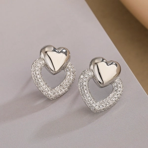 Vue macro de boucles d'oreilles cœur plaqué or avec zircons étincelants et perles fines