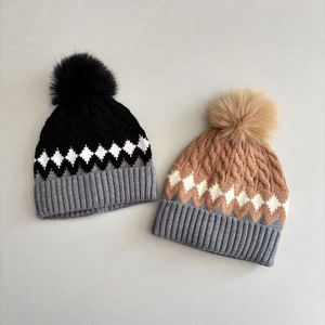 Detail of diamond pattern knit hats with faux fur pom-poms for winter warmth
