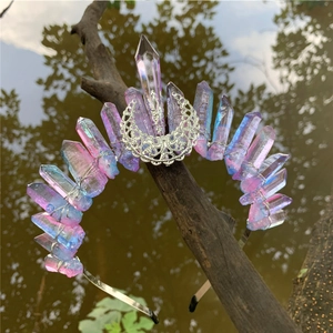 Iridescent crystal moon crown headband resting on a natural branch over water