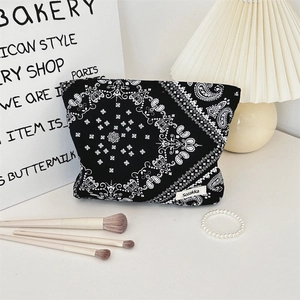 Close-up of black floral paisley makeup bag with zipper closure and white logo detail