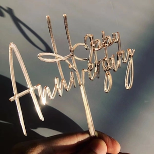 Close-up of rose gold acrylic Happy Anniversary cake topper with elegant script