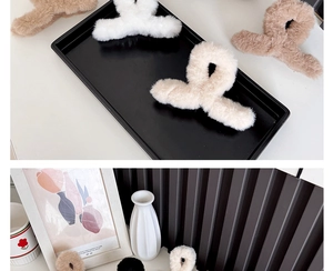 Detail view of plush beige and white faux rabbit fur hair claw clips in a cozy setting