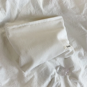 Close-up of white corduroy makeup bag with zipper and minimalist brand label on fabric