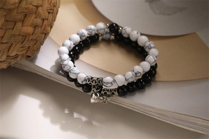 Detail shot of couple bead bracelets with magnetic heart charms on a book page