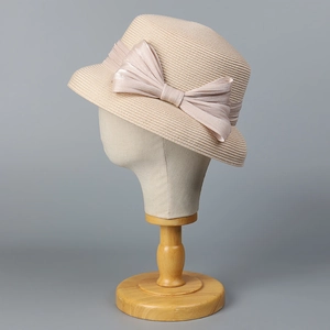 Dettaglio di un elegante cappello cloche in paglia beige con un grande fiocco decorato