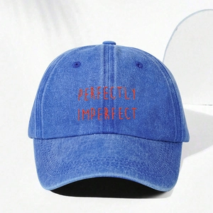 Detail of perfectly imperfect orange embroidery on washed denim blue baseball cap