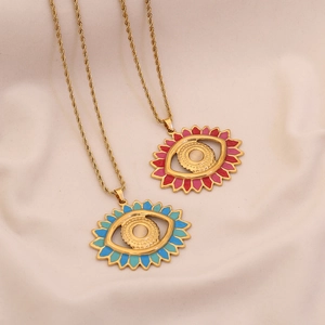 Gold evil eye necklace set with pink and turquoise enamel pendants on beige fabric