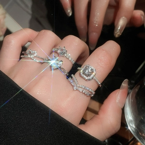 Close-up of sparkling zircon heart and crown ring set worn against dark background