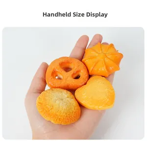 Close-up showing the size of realistic orange resin cookie and pumpkin pendants in hand
