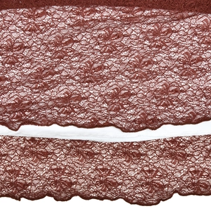 Detailed view of floral brown lace fabric with wavy edges and soft white inner lining
