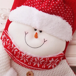 Detail of red and white knit Christmas stocking featuring a 3D plush snowman with wood button