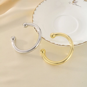 Detail of minimalist gold and silver ball-end open bracelets on elegant silk background