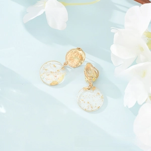 Macro shot of gold hammered metal and transparent resin earrings with gold leaf accents