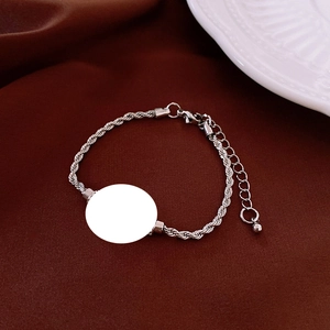 Detailed close-up of a silver twist rope bracelet with circular charm and lobster clasp