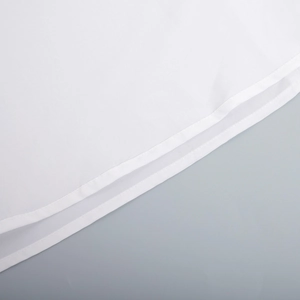 Detailed macro view of the double-stitched hem on a white cotton maxi dress fabric