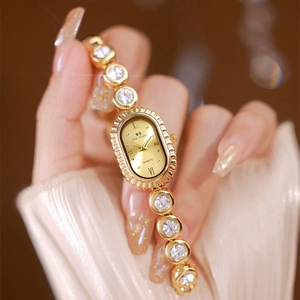 Close-up of elegant gold oval watch with crystal strap worn on a woman wrist