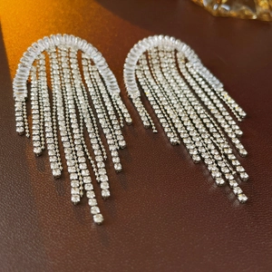 Macro detail of silver tassel earrings with sparkling cubic zirconia on brown leather