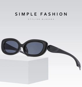 Black Y2K oval sunglasses displayed at a 45-degree angle on a white geometric stand
