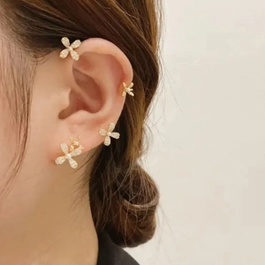 Detail of gold-plated floral ear clip featuring cubic zirconia and pearls on female model