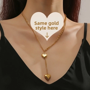 Detail of a gold double-layered heart Y-shaped necklace worn on a female model