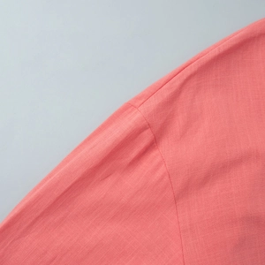 Close-up of coral pink cotton fabric showing natural fiber texture and stitching