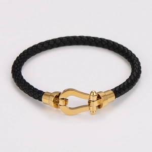 Dettaglio di un bracciale in pelle intrecciata nera con chiusura a ferro di cavallo