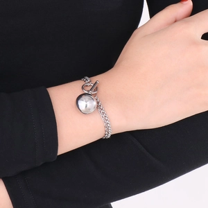 Detail eines silbernen Doppelkettenarmbands mit Kugelanhänger und OT-Knebelverschluss