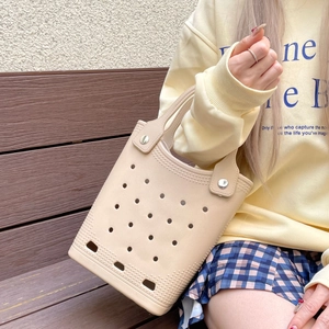 Macro shot of beige EVA beach tote bag featuring circular cutouts and rivet details