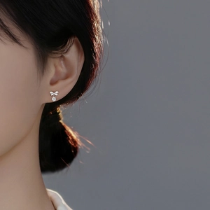 S999 Sterling Silver bow earrings with a round zircon pendant shown on a model