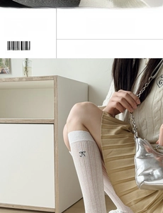 Detail of white knit crew socks with vertical stripes and black bow embroidery accent