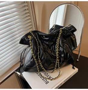 Quilted black leather tote bag with gold chain strap detail and drawstring side feature