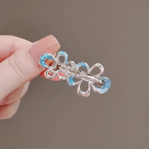 Detail of silver metal hair clip with blue floral enamel patterns and star shape