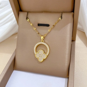 Detail of gold clover pendant with sparkling white cubic zirconia on white satin