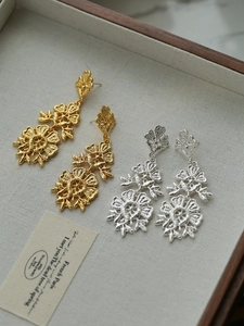 Detail of vintage flower tassel earrings with intricate lace-like texture in gold and silver