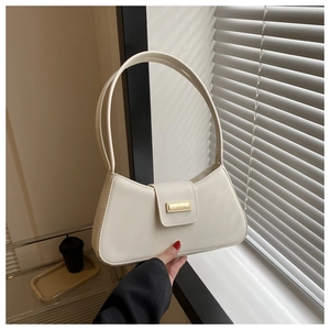 Detailed close-up of cream baguette bag with minimalist gold metal buckle and smooth leather
