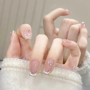 Dettaglio di unghie finte sfumate nude con punte French glitter argento e piccoli strass