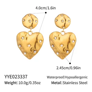 Detail of gold heart drop earrings with irregular texture and star-set zircon accents